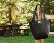 Picture of tote bag hanging on a fence post and a picnic table in the background