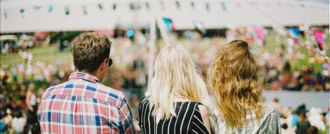 three people standing with their back turned to the camera at a summer festival advert for promo products